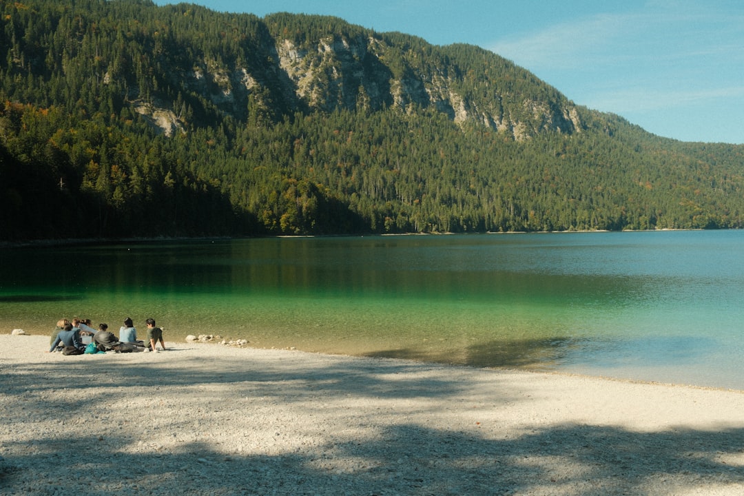 People relaxing on a beach by a clear lake