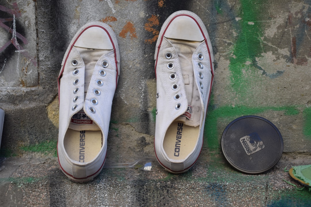 Pair of white converse sneakers with unlaced eyelets.