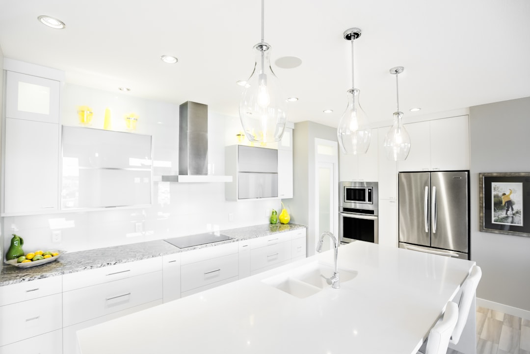 Modern white kitchen with island and stainless steel appliances.