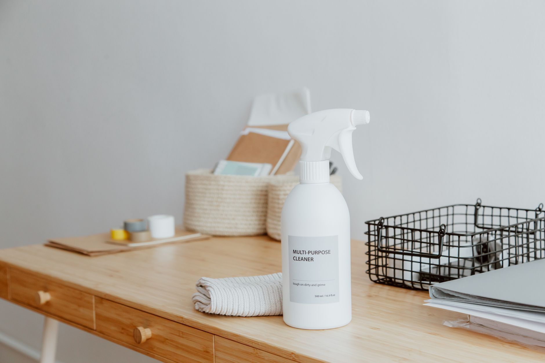 Minimalist desk with a focus on a multipurpose cleaner, office supplies, and storage solutions.